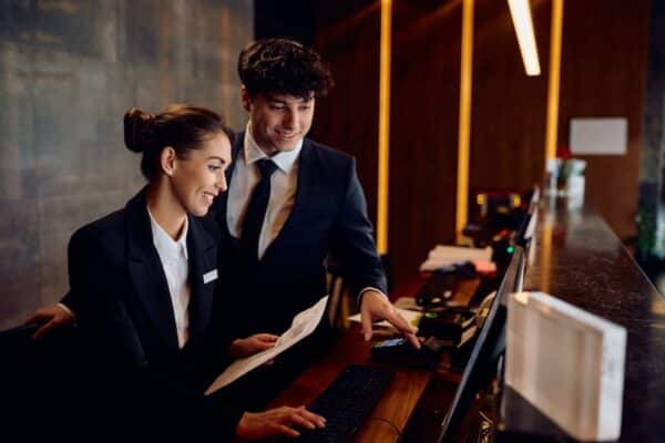 receptionists cooperating while working on computer at hotel front desk