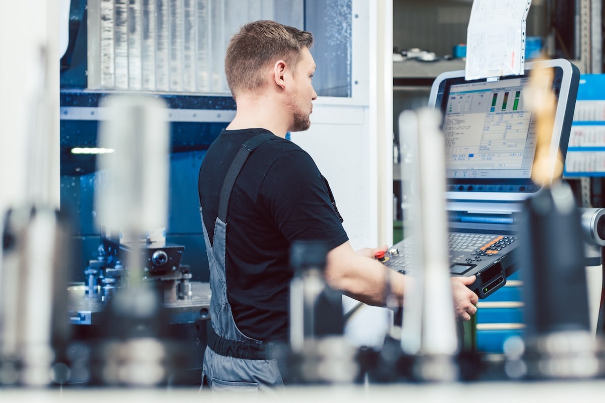 Manufacturing worker using a CNC machine to perform critical duties